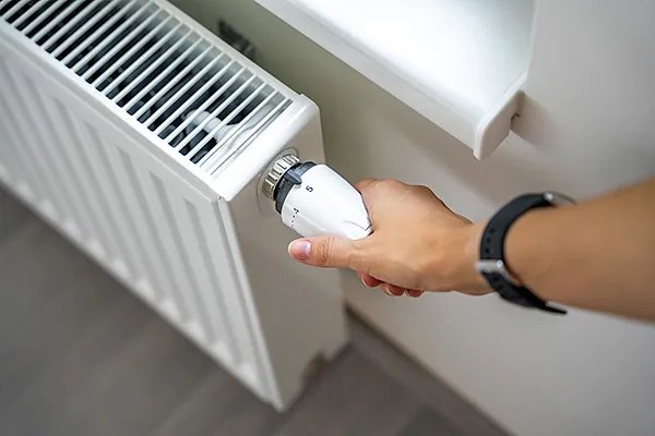 Person dreht Heizung wärmer